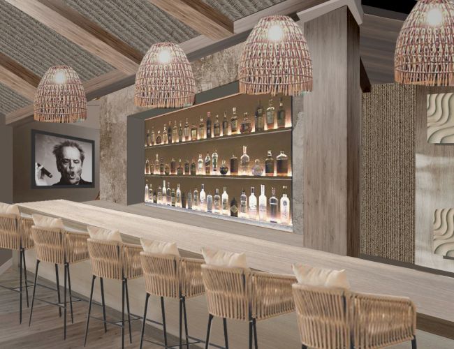 A modern bar with wooden stools, bottle display, wicker light fixtures, and wall art creates a cozy atmosphere.