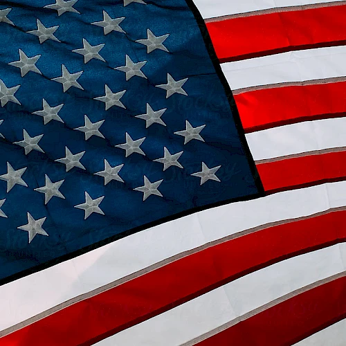 A close-up of the United States flag, with red and white stripes and white stars on a blue field, waving.